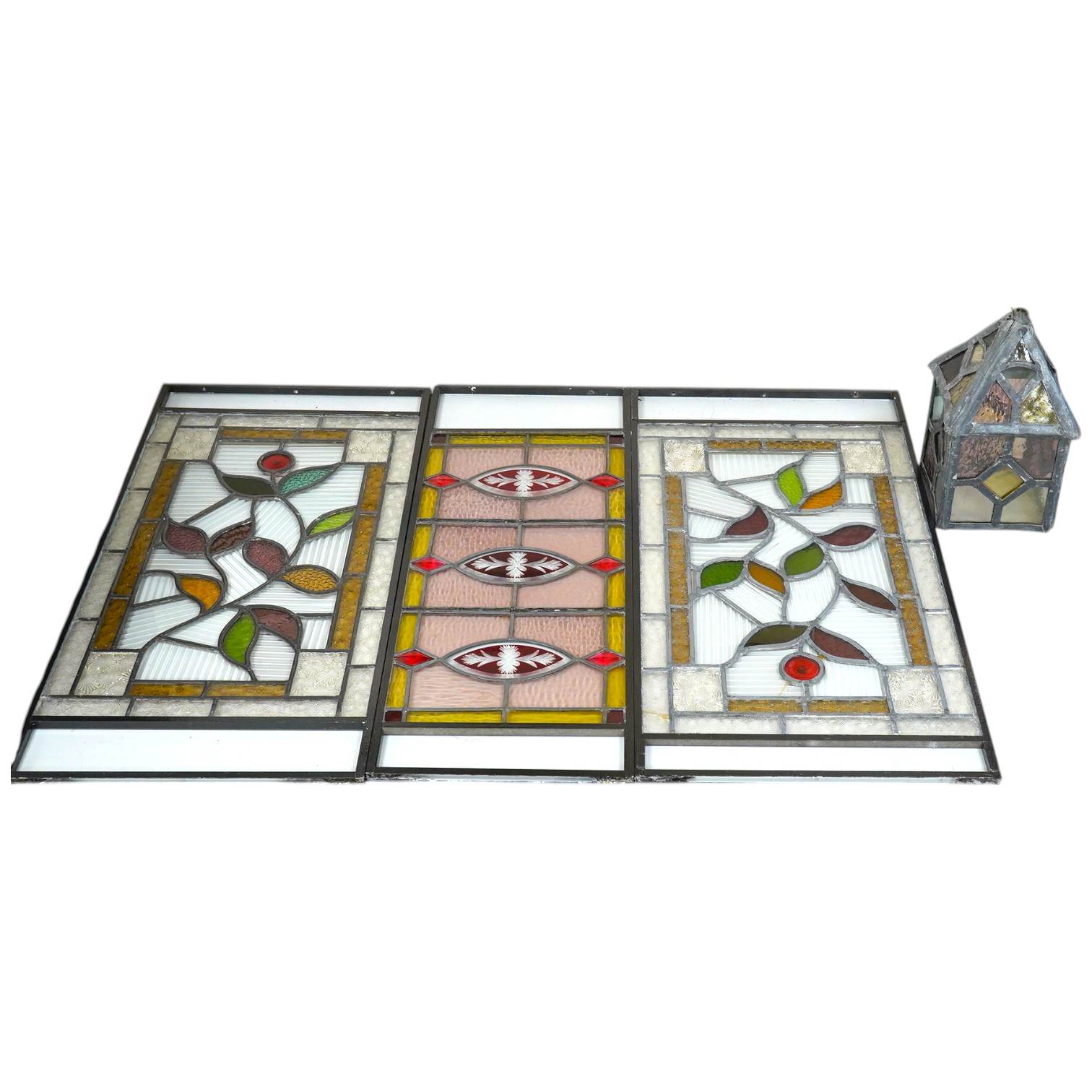 Three stained glass panels in metal frames and a stained glass lantern, longest 55.5cm. Condition - two panels elements of glass broken, lantern good